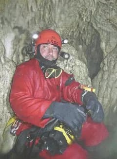 Speleosubacqueo in muta stagna rossa e casco con le luci dentro una grotta