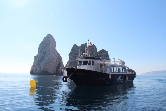 La barca del diving ormeggiata accanto ai faraglioni delle isole Medas