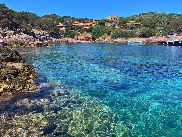 Caletta dall'acqua trasparente con le case dell'isola sul promontorio