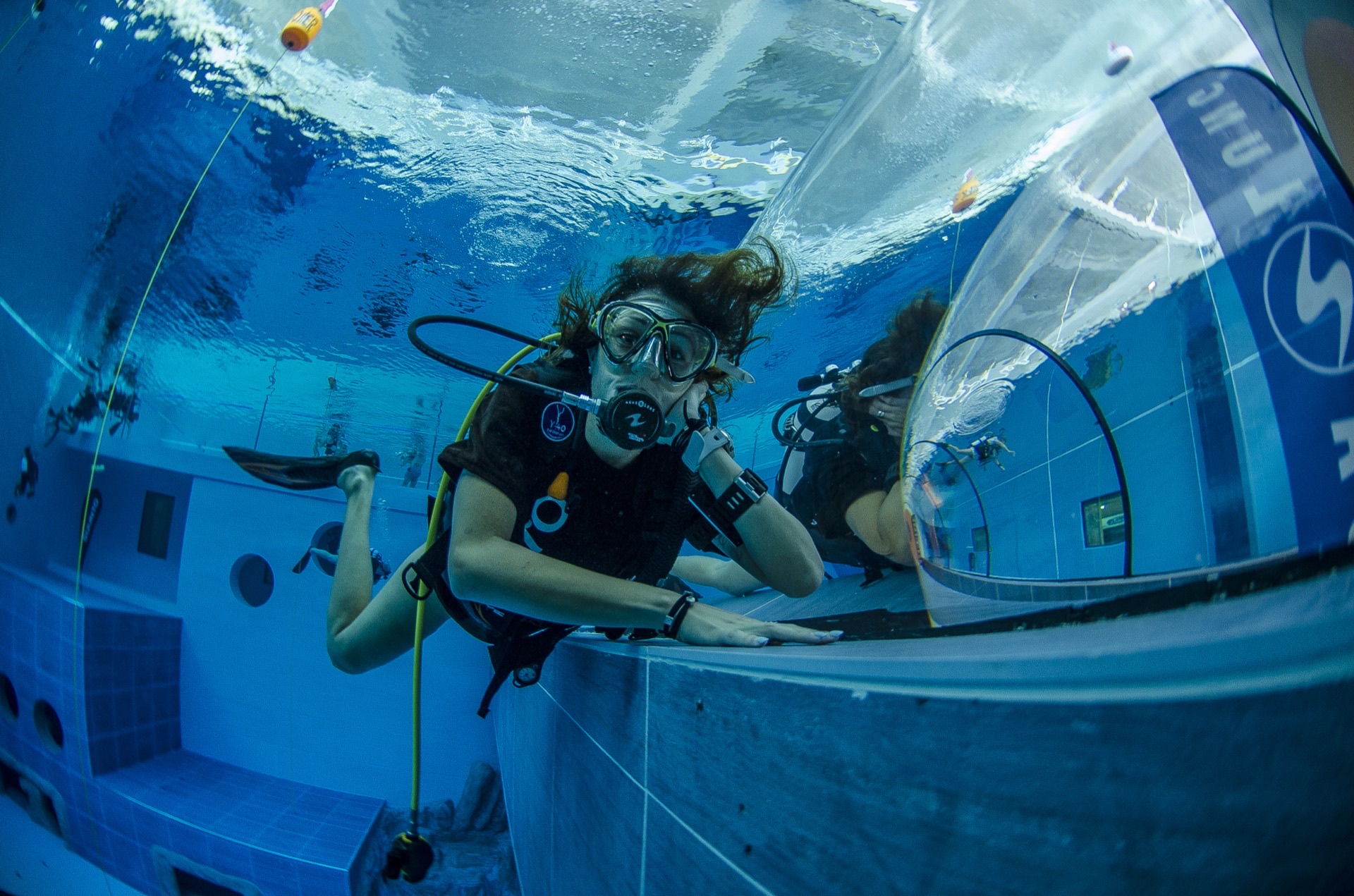 Subacquea si affaccia al tunnel trasparente della piscina Y-40