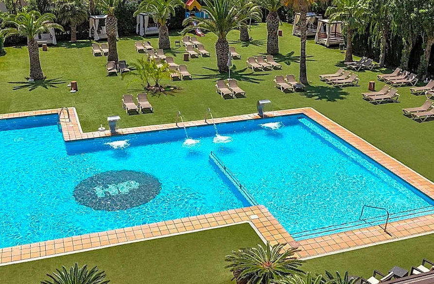 La piscina esterna dell'hotel circondata da palme e lettini