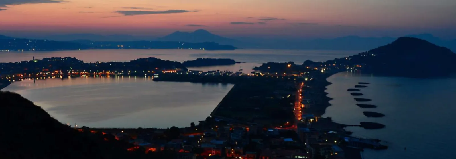 Il golfo di Pozzuoli al tramonto, con il lago Lucrino e le luci della costa
